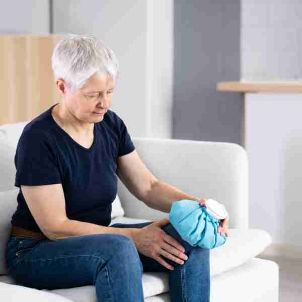 Woman Holding Cool Gel Pack On Knee For Pain Relief
