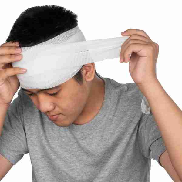 Young man placing bandage on his head