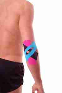Rear view of an athlete wearing k tape on his elbow. Using k tape for tennis elbow pain allows for a wide range of motion with little restriction of movement