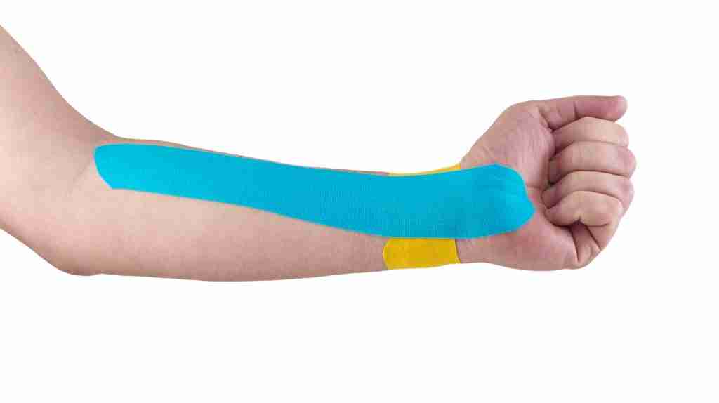 A close up view of a wrist srapped with kinesiology tape. This is a popular choice of athletic tape for wrist injuries due to its high elasticity and ability to accommodate the wrist joint's wide range of motion.
